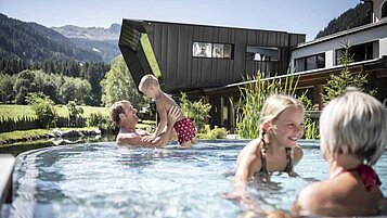 Familie planscht im Outdoor-Pool des Alphotel Tyrol Wellness & Family Resort in Südtirol.
